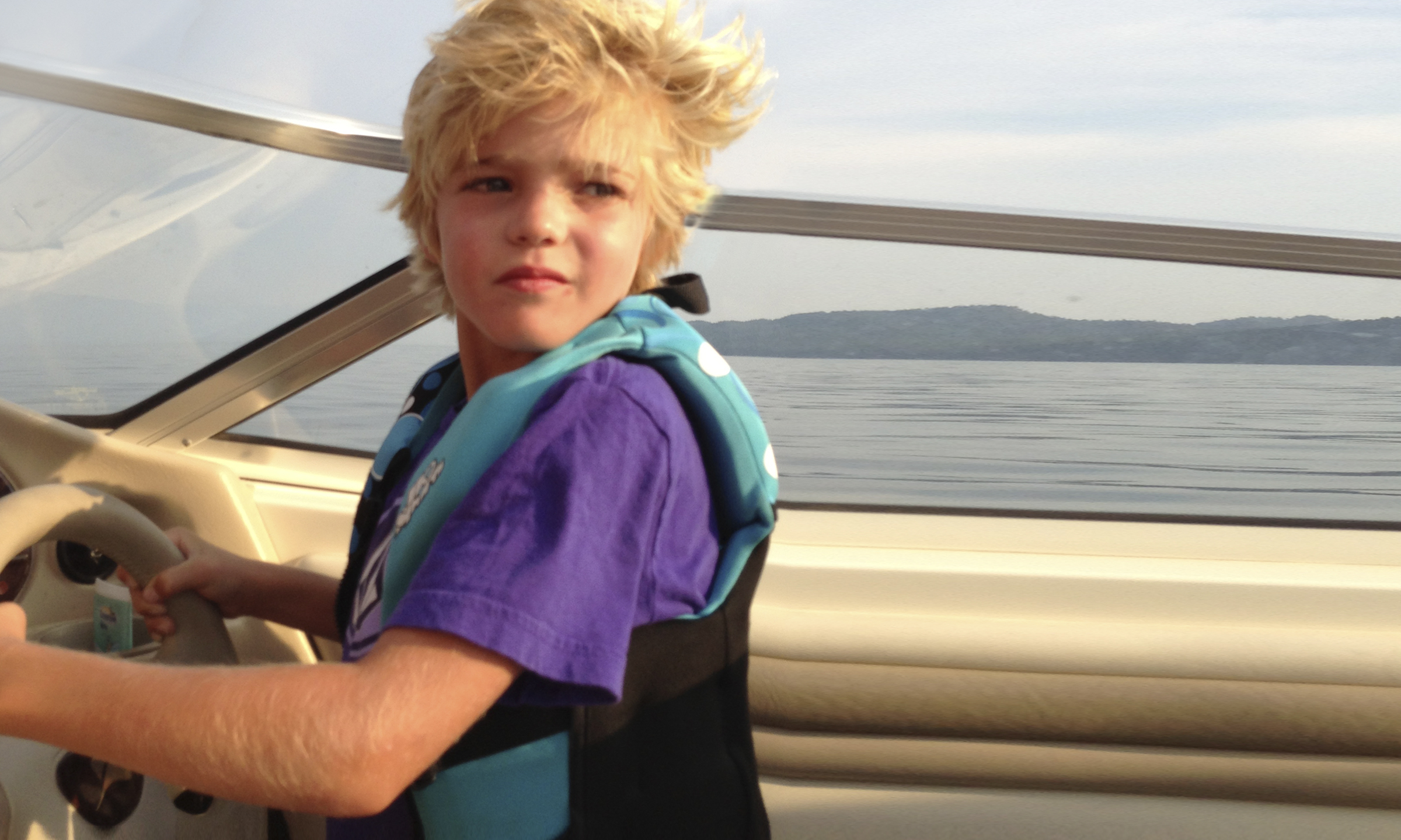 Boy steering a boat on a lake